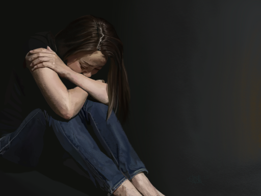 A person sitting on the floor, hugging their knees and looking down in a dark setting.